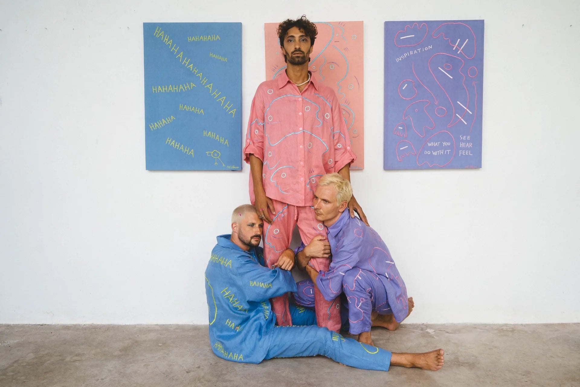 People wearing blue, pink and lilac Soft Code linen works beside paintings