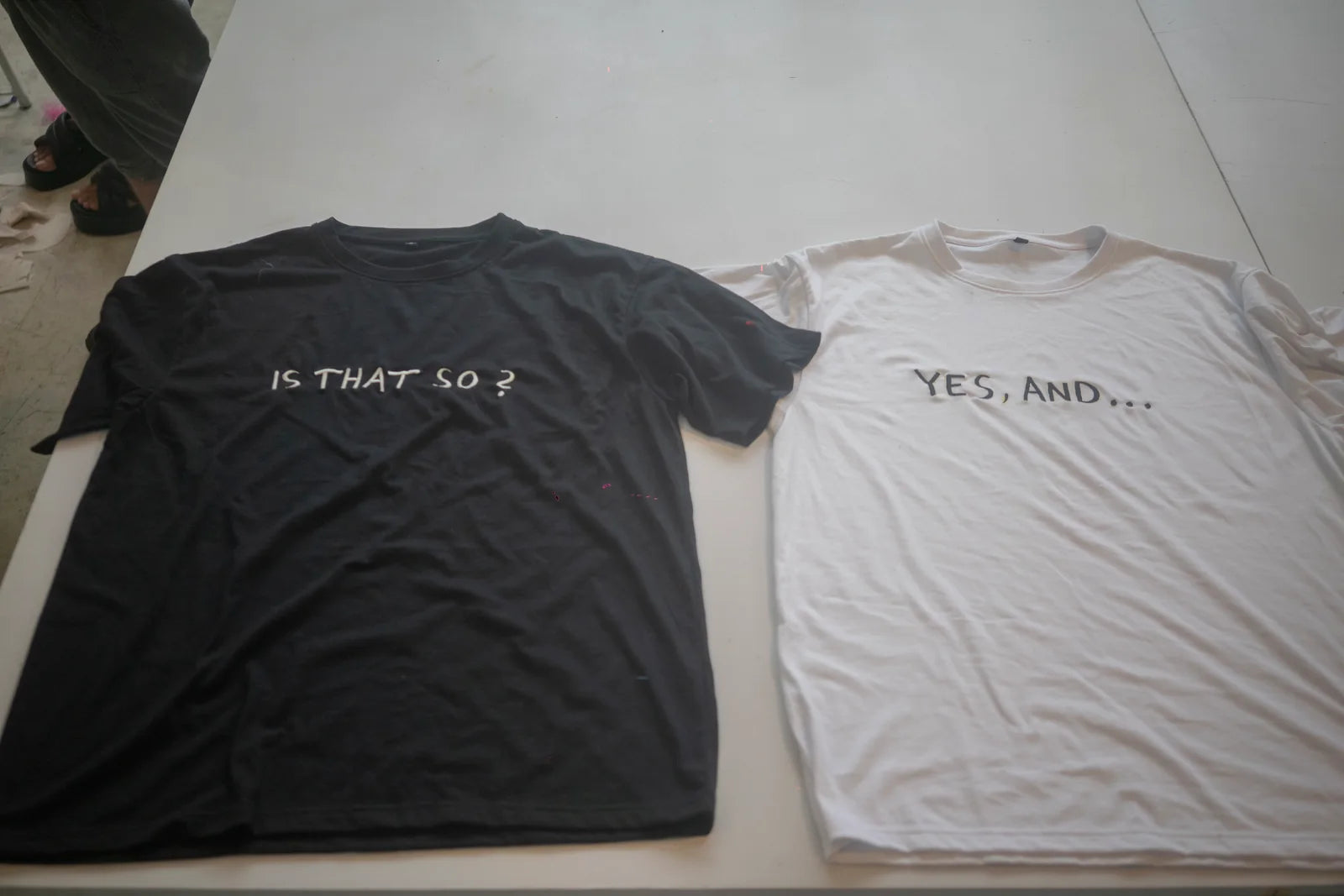 Two finished shirts carrying the words NO THAT SO and YES AND