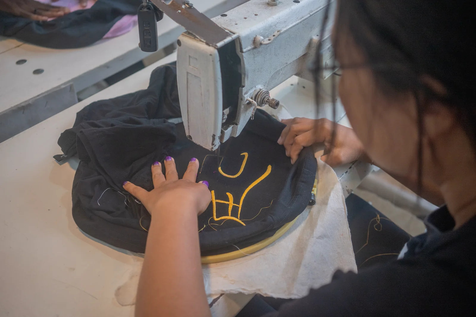 Yellow embroidery being stitched into a black garment