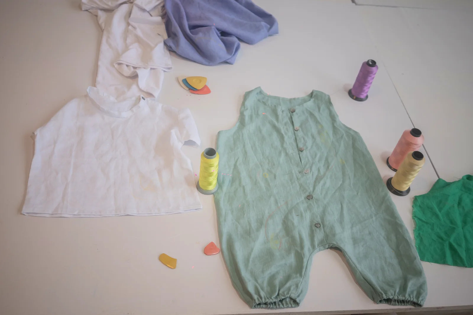 A pale green garment with thread and drawing tools