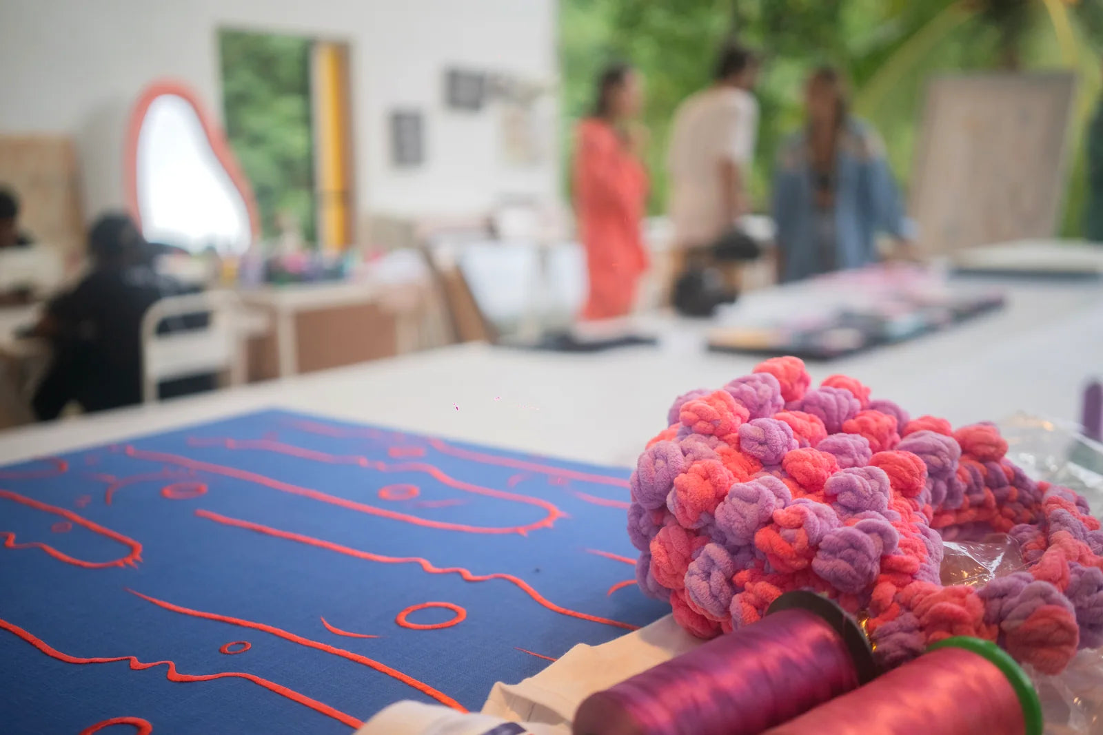 A blue embroidered work beside a playful sculptural object