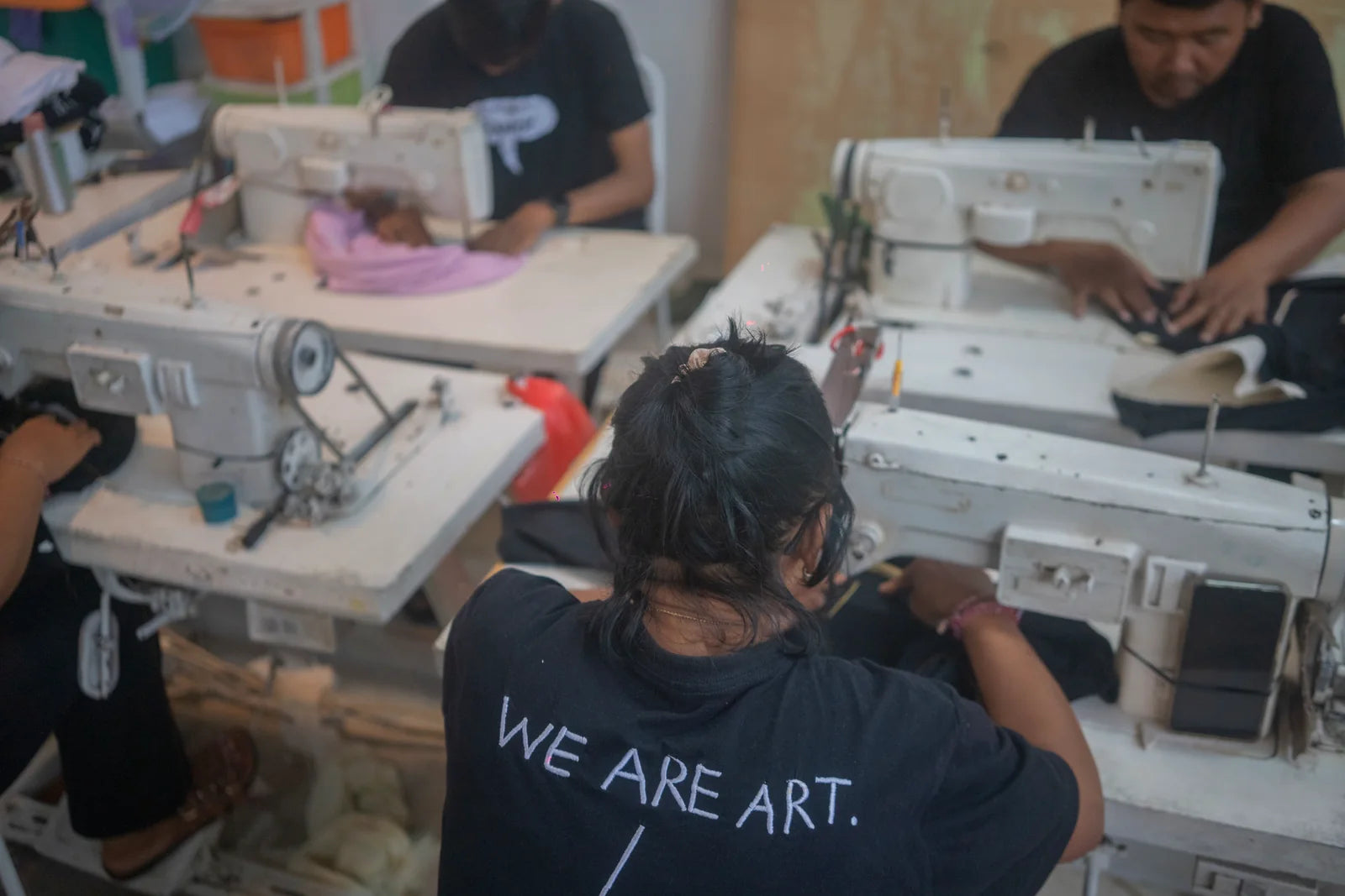 The embroidery team working while a participant wears WE ARE ART