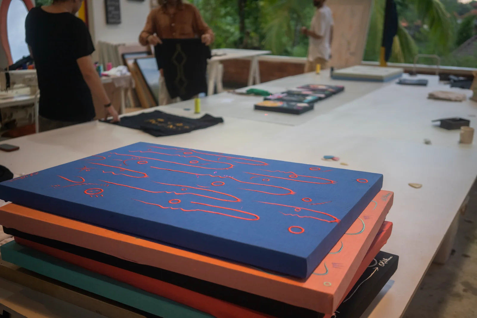 Stacks of embroidered and painted works ready in the studio
