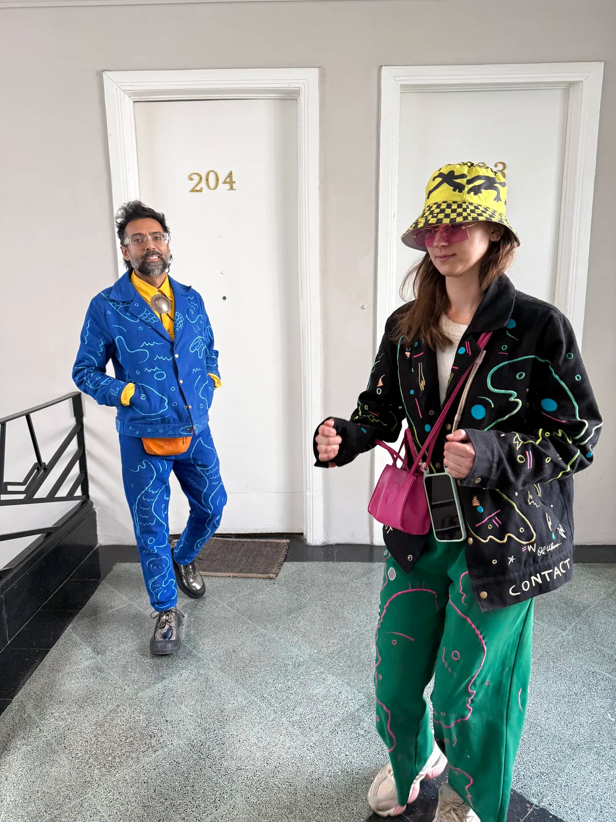 Varun and Morta laughing beside the apartment doors