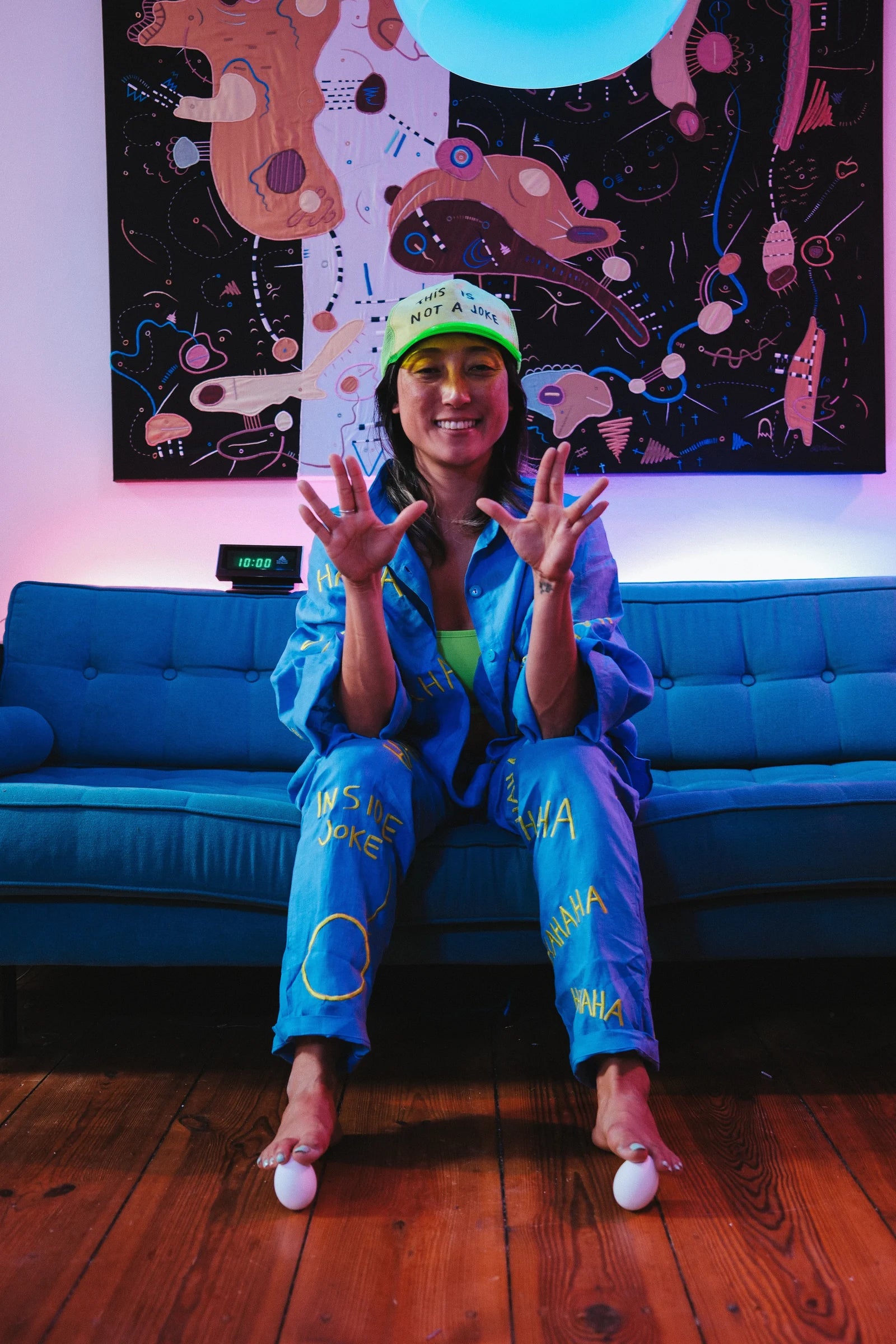 KOTOE seated on a blue sofa in the HA HA HA set