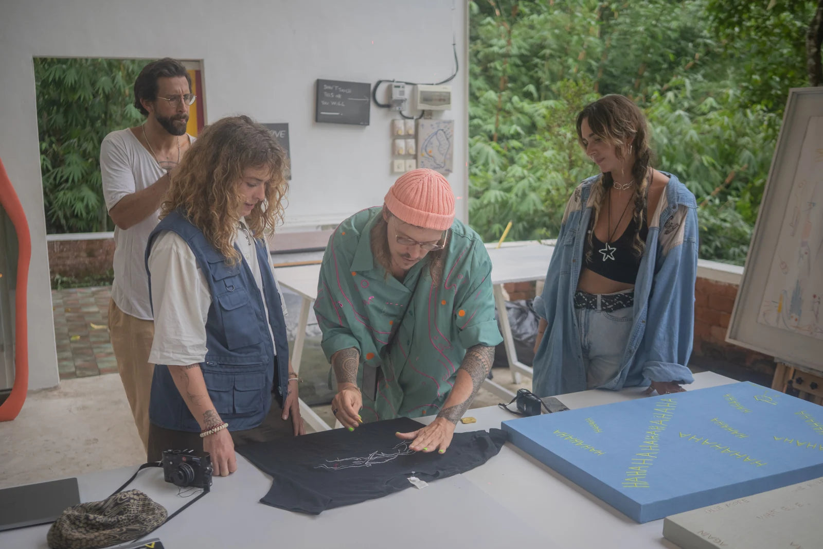 Visitors gathered around the table, drawing on a garment at AIR