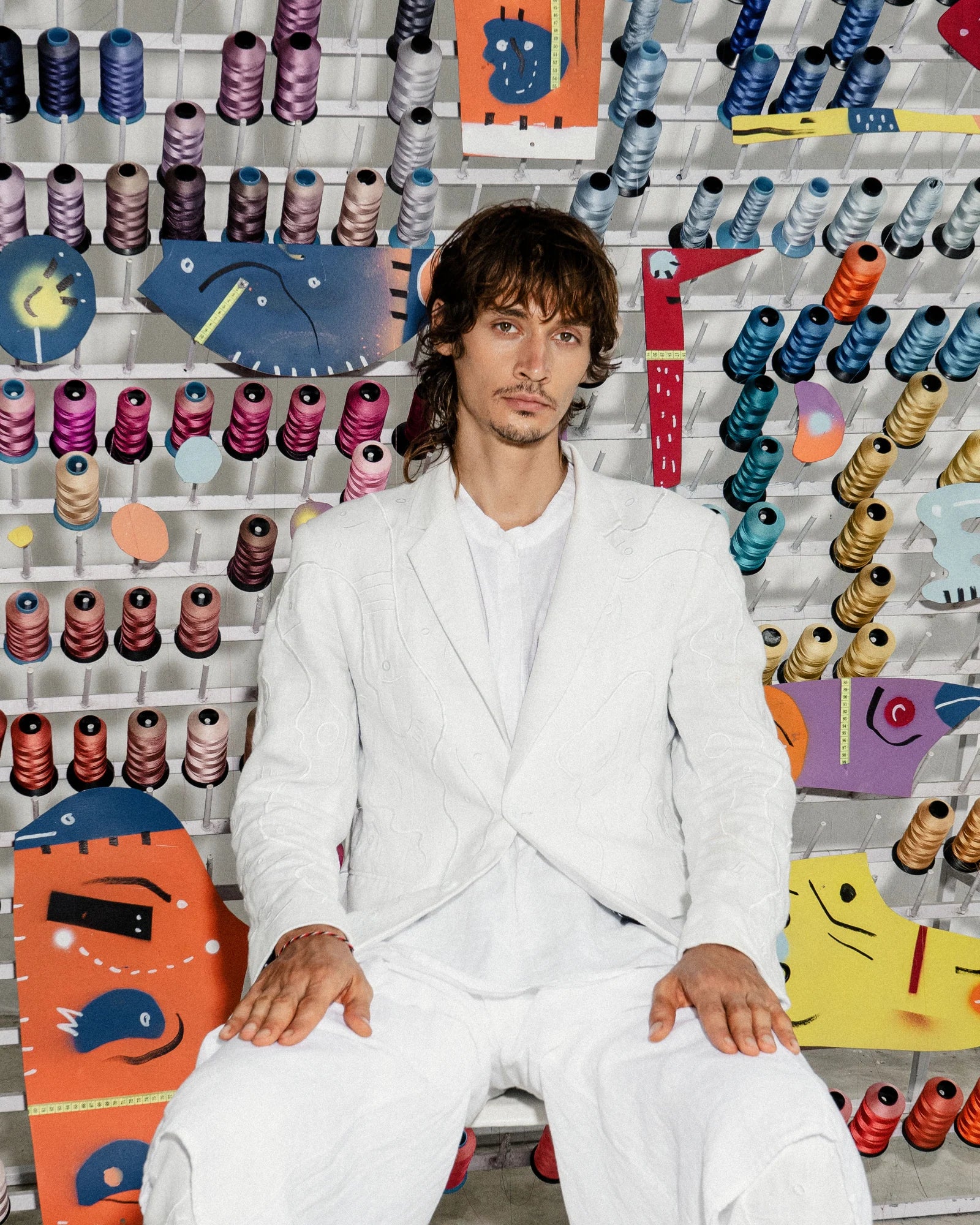 A person wearing white in front of colourful thread spools in the Antidote campaign