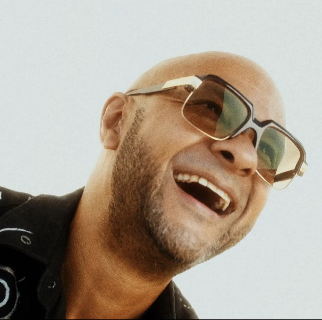 Close portrait of George Evelyn in sunglasses and an embroidered black shirt