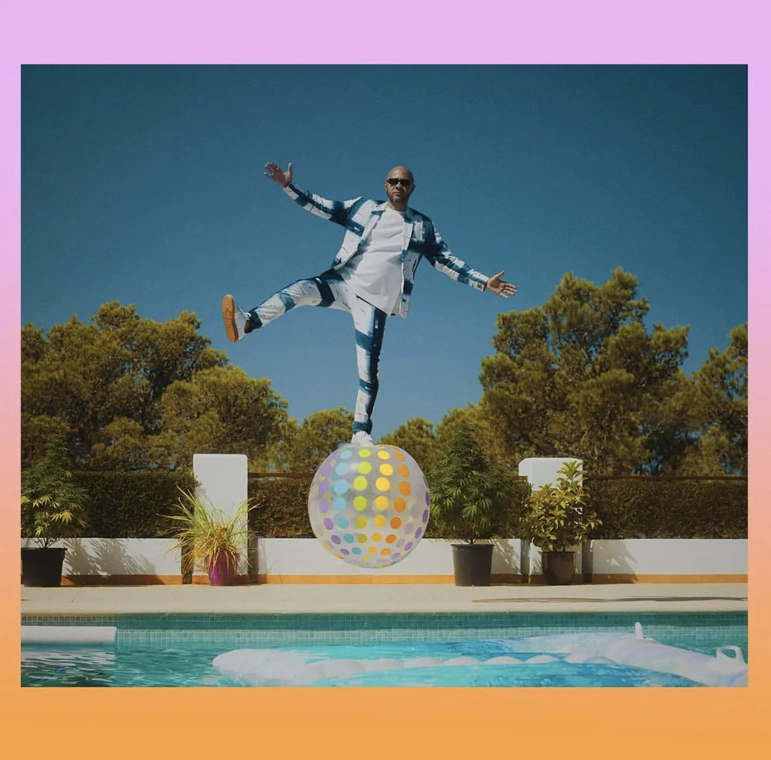 George Evelyn balancing above a coloured sphere in a pale UKENA suit